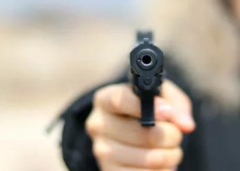 Woman pointing a gun at the target on soft background.
