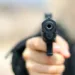 Woman pointing a gun at the target on soft background.