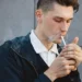 Fashion hipster male model smoking cigarette on the street