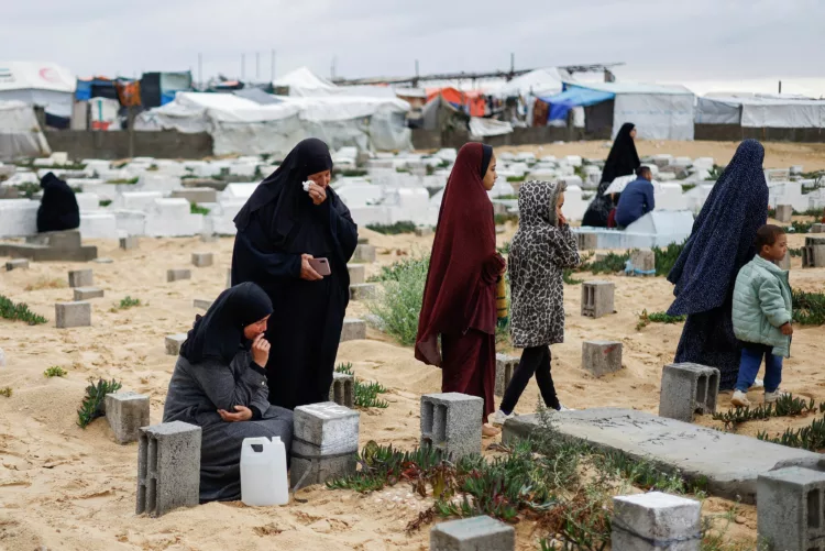 Palestinian women visit graves of people who were killed in the ongoing conflict between Israel and Palestinian Islamist group Hamas, on the day of Eid al-Fitr, in Rafah, in the southern Gaza Strip April 10, 2024. REUTERS/Mohammed Salem TPX IMAGES OF THE DAY