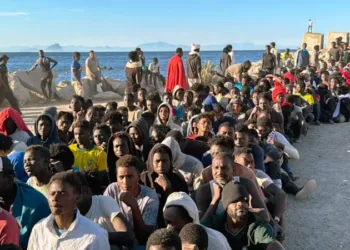 Cientos de migrantes, procedentes de Marruecos, fueron fotografiados haciendo fila en una playa de Ceuta para recibir ayuda.