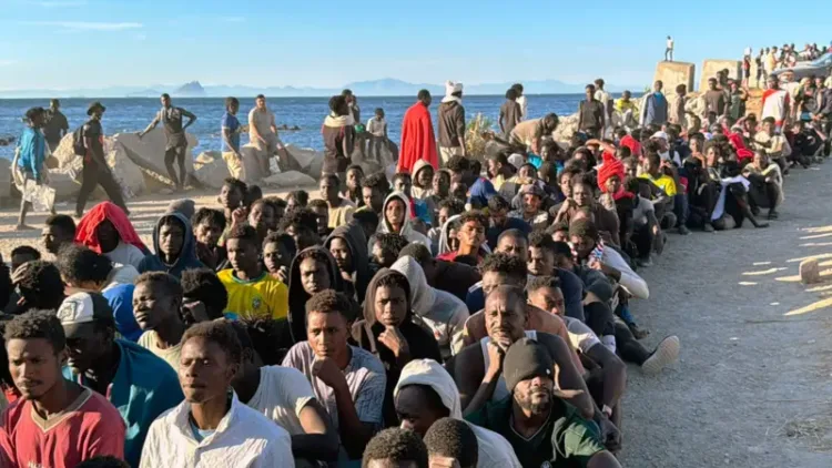 Cientos de migrantes, procedentes de Marruecos, fueron fotografiados haciendo fila en una playa de Ceuta para recibir ayuda.