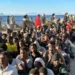 Cientos de migrantes, procedentes de Marruecos, fueron fotografiados haciendo fila en una playa de Ceuta para recibir ayuda.